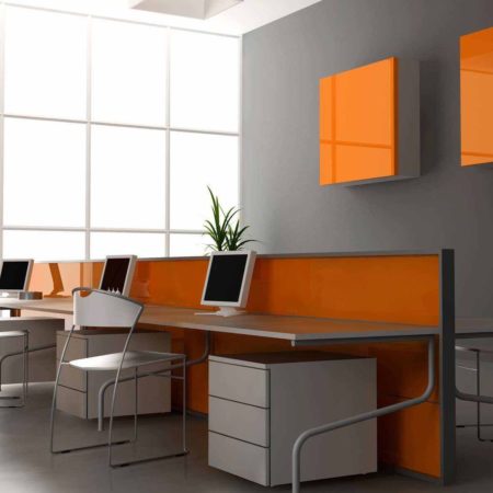 Photo of a modern grey and white office with orange accents. Three workstations are shown.